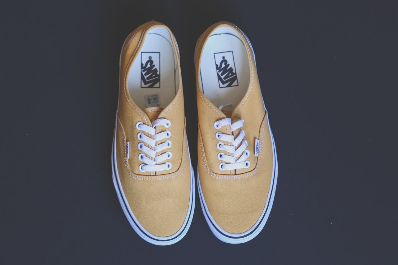 who-we-are Pair of stylish yellow sneakers on a black background showcasing fashion and footwear design.